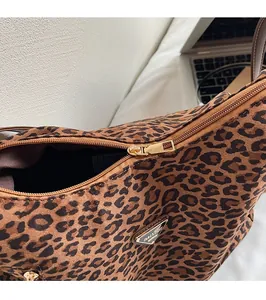 Detailed close-up of smooth gold zipper and leopard print texture on a shoulder bag