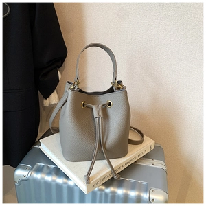 Detail view of gray pebbled leather bucket bag with gold eyelets and drawstring closure