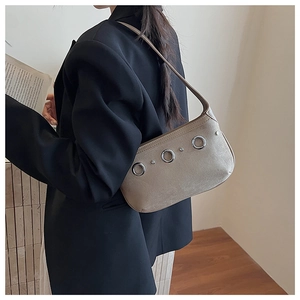 Detail of suede crossbody bag with silver rings held by model in black blazer