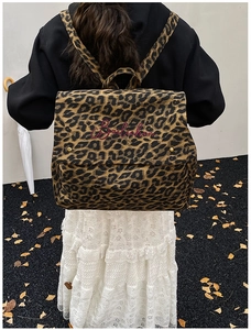 Outdoor view of large leopard print canvas backpack with embroidered brand detail