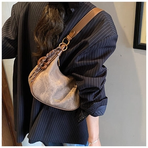 Brown leather moon bag with retro texture and gold metal ring detail on the shoulder strap