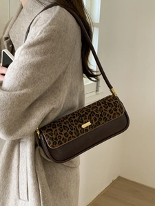 Retro leopard print baguette bag with brown leather and gold buckle worn on shoulder