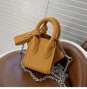 Detailed macro view of mustard yellow pebbled leather mini bucket bag with silver chain