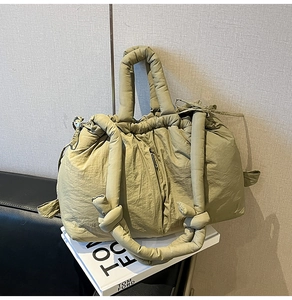 Detailed macro view of olive green quilted down tote bag with padded handles and drawstring