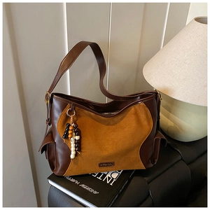 Detail of suede hobo bag with contrast stitching and decorative ethnic wooden beads