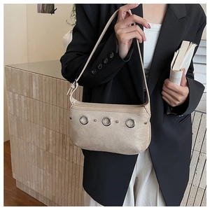 Detail showing apricot suede material and silver eyelet rings on a fashion shoulder bag