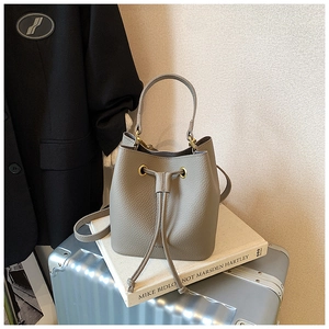 Detail of grey pebbled leather bucket bag with drawstring closure and gold hardware