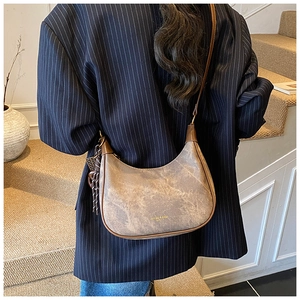 Detailed shot of brown textured leather shoulder bag with decorative woven tassel