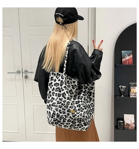 Detail of plush leopard print tote bag featuring a golden oval metal logo plate