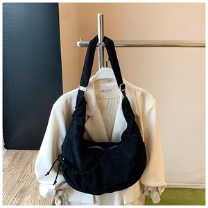 Close-up of black pleated dumpling bag with drawstring details and minimalist shoulder strap