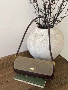 Retro baguette shoulder bag in olive green suede and dark brown leather on wood table