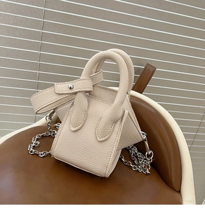 Detailed macro view of beige lychee texture leather mini bucket bag with silver chain strap