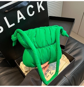 Detailed view of neon green puffer tote bag with ruched texture in a black gift box