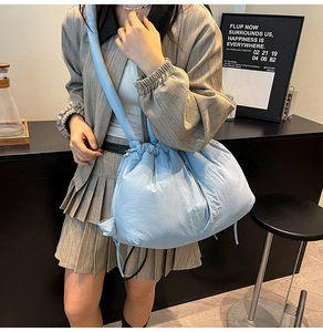 Close-up of light blue puffy tote bag with drawstring closure and glossy nylon fabric