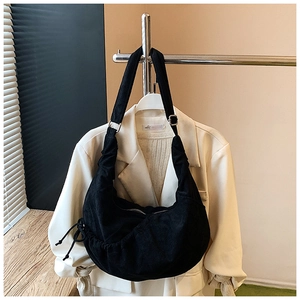 Detail of black pleated croissant bag with adjustable strap on cream blazer
