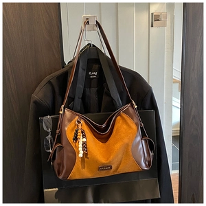 Detail of vintage patchwork tote bag in brown leather and yellow suede with bead charm