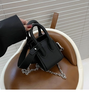Close-up of black litchi textured leather mini bucket bag with silver chain strap
