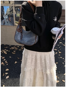 Chic washed denim hobo bag featuring brown leather trim and a knotted strap detail