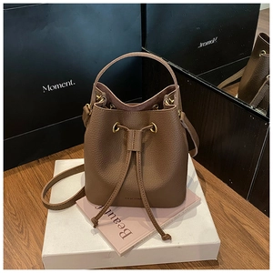 Detail of brown litchi pattern leather bucket bag with drawstring and golden eyelets