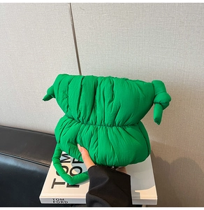 Detail of emerald green quilted puff handbag with soft cloud texture and knotted strap