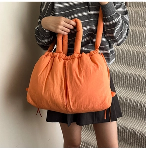 Detailed view of an orange padded tote bag featuring a drawstring closure and soft handles