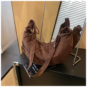 Detail view of dark brown suede crescent bag with side drawstring and adjustable strap