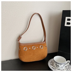 Detail of suede crossbody bag featuring silver ring accents and metallic rivet trim