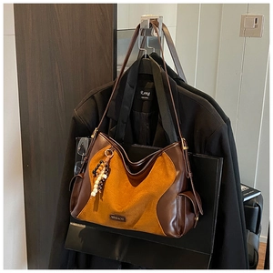 Detail of suede and smooth leather tote bag with wooden bead tassel and retro metal hardware