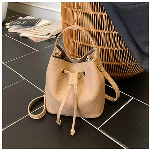 Close-up of lychee grain leather bucket bag with drawstring and golden metal eyelets