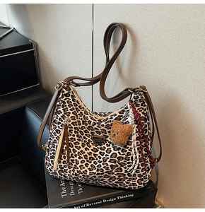 Detail of leopard print hobo bag with a brown teddy bear charm and adjustable leather strap