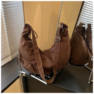 Detail of dark brown suede tote with tassel drawstring and adjustable shoulder strap buckle