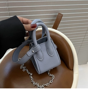 Close-up of blue pebbled leather bucket bag with silver chain and dual handles