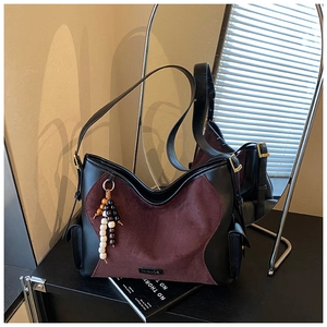 Detail of burgundy suede tote bag with contrast leather and vintage wooden bead charm