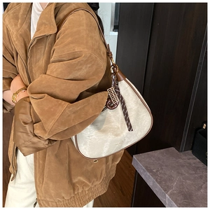 Close-up of crescent underarm bag in beige textured fabric and brown leather trim