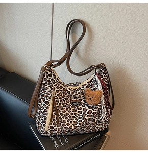 Detail of leopard print hobo bag with brown leather strap and cute bear charm