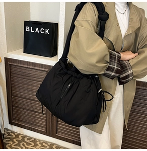 Detail of black puffer tote bag with side drawstring and decorative zipper detail