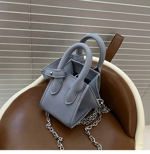 Detailed close-up of grey-blue pebble leather bucket bag with silver chain and rivet details