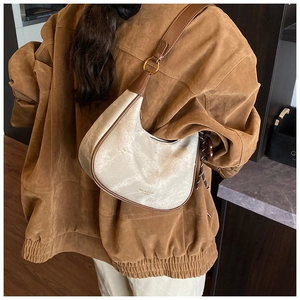 Detail of retro hobo bag in cream with dark brown leather trim on model shoulder