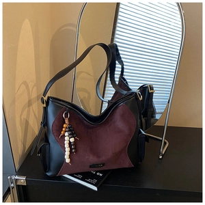 Detail of burgundy suede and black leather patchwork bag with bead charm and logo