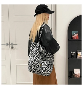 Close-up of zebra print canvas tote bag with gold logo and matching shoulder strap
