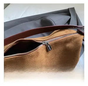Detail of silver zipper and premium suede texture on a brown tote bag with leather handle