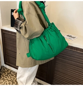 Detailed view of the green quilted puffer bag with large knot strap and side zipper