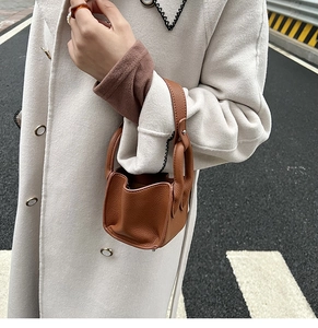 Close-up of brown pebbled leather mini bucket bag with silver hardware and handle detail