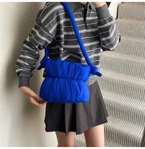 Detail of royal blue puffy shoulder bag showing soft pleated texture and thick round strap