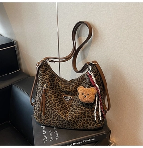 Detail of leopard print tote bag with brown leather trim and cute bear charm pendant