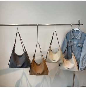 Detailed display of canvas crescent tote bags in charcoal, brown, khaki, and cream colors