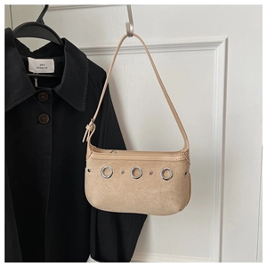 Detailed close-up of khaki suede handbag with silver metal eyelets and adjustable strap