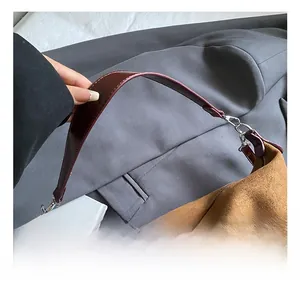 Detail of soft brown suede tote bag with contrast burgundy handle and silver metal buckle