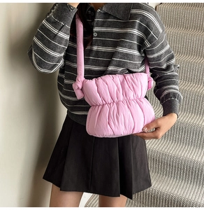 Detail of pink puffy quilted crossbody bag with stylish knot design on shoulder strap