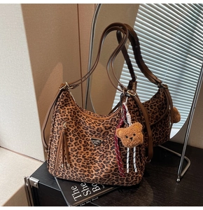 Detail shot of leopard print tote bag with plush bear charm and leather tassel zipper